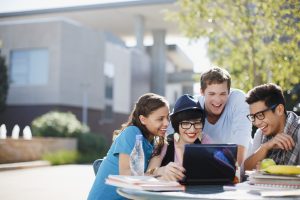 Students using laptop together outdoors